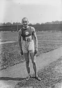Photographie en noir et blanc d'un athlète en tenue, crâne rasé.