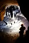 Homme debout dans une galerie souterraine avec stalagmites et stalactites