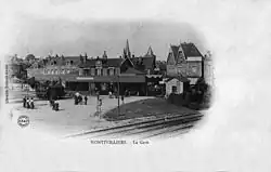 intérieur de la gare, vers 1900, avec personnages et locomotive à vapeur ; au premier plan, la ligne à double voie.
