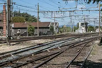 Vue des voies au nord de la gare, et, à l'arrière-plan, derrière le poste d'aiguillage, la voie en provenance de Firminy de la ligne de Firminy à Saint-Rambert-d'Albon.