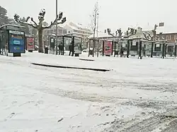 Photographie en couleurs de plusieurs arrêts de bus sous la neige.