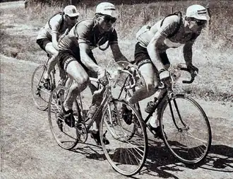 Photo en noir et blanc de trois cyclistes en échappée.