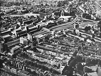 Montage photographique en noir et blanc d'une autoroute bordée d'immeubles modernes au cœur d'une ville dense.