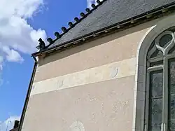 Vue d'une frise sur un mur, ornée de blasons autrefois peints