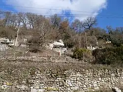Vue de caves creusées à flanc de coteau et fermées par des murs modernes.