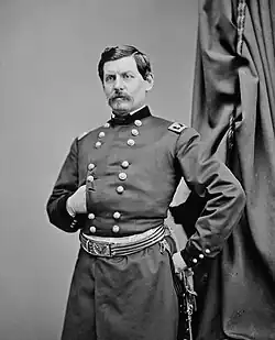 Photo of man with goatee and his right hand thrust into a dark military uniform