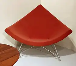 C'est une chaise rouge qui semble en cuir de forme triangulaire et arrondis