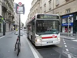 Photographie d'un arrêt de bus matérialisé par un totem, devant lequel est stationné un bus de la ligne 91 à destination de la gare Saint-Paul.