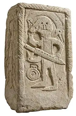 Stèle funéraire de Niederdollendorf, VIIe siècle. Guerrier tenant une épée d'une main et se coiffant de l’autre avec un peigne.