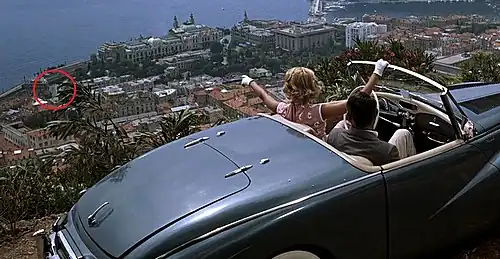 Grace Kelly dans le film La Main au collet d'Alfred Hitchcock, pointant du doigt l'avenue qui portera son nom.