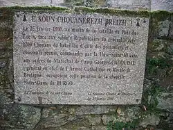 Photographie d'une plaque commémorative sur un mur en pierre.