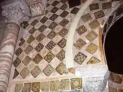 Photographie des carreaux de céramique lustrée, monochromes et polychromes, qui ornent le mihrab et son mur. Leurs décors variés comportent divers ornements géométriques, floraux et végétaux.