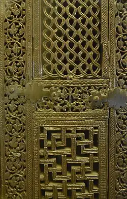 Photographie de deux panneaux du minbar. Ces panneaux sont entourés de bandeaux à décor de rinceaux. Les pièces, réunies par des tenons et des mortaises, sont consolidées par des ferrures.