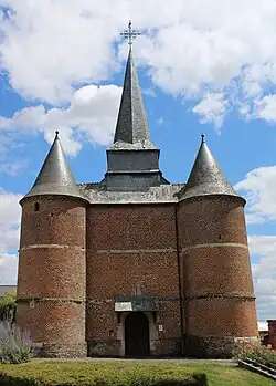 Façade de l'église avec ses deux tours fortifiées symétriques percées de meurtrières. Le clocher octogonal se situe au-dessus du porche.