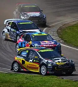 Quatre voitures colorées dérapent pendant un virage.