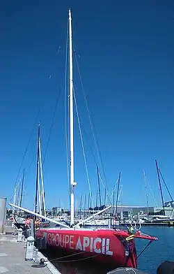 Vu de trois quarts face, en entier, voilier rouge amarré au ponton.