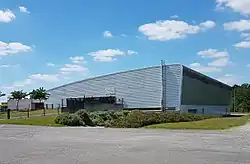 Photographie en couleurs d'un grand bâtiment moderne en métal et verre.
