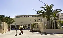 Un bâtiment blanc à toit plat, protégé par des grilles