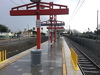 Vue du quai central de la station. L'œuvre, des totems de couleur rouge, est visible.