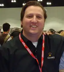 Portrait d'un homme souriant, avec un badge autour du cou.