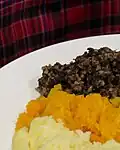 Le haggis et son accompagnement de légumes, devant le tartan du clan MacAlister.