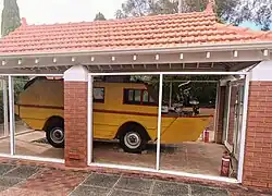 Photographie d'un véhicule jaune, amphibie, exposé derrière une vitre.