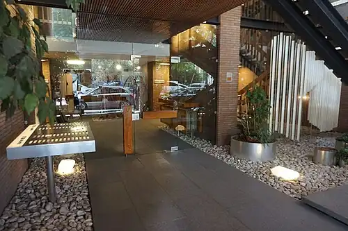 Photographie couleur du hall d'entrée de la résidence Vincennes : parement brique, dalle béton, porte en verre