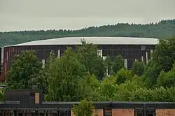 L'amphithéâtre olympique de Hamar derrière des arbres.