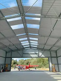 Le même hangar : devant l’entrée, un avion ultra léger se fait admirer par des enfants.