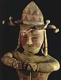 Haniwa d'homme en chapeau à clochettes, jambes croisées, armé, pigment rouge (h. 91 cm). Iwaki, Fukushima, VIe&nbsp;siècle (?), Iwaki High School