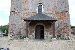 Le portail de style roman en pierre calcaire en plein cintre protégé par un auvent.