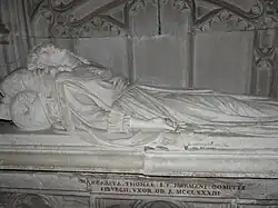 Statue d'une femme en robe couchée sur le dos, une main sur le ventre et l'autre le long du corps.