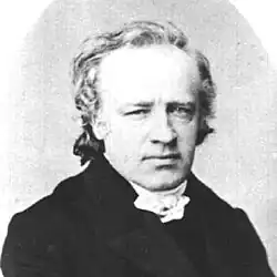 Photo en noir et blanc d'un homme de trois quarts face, un œil légèrement fermé.