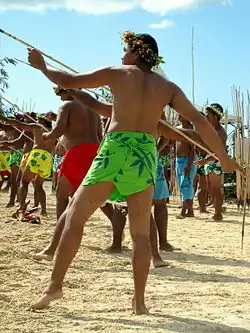 Des hommes sur une plage, tenant des javelots et s'apprêtant à les lancer