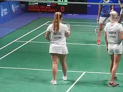 de joueuses estoniennes de dos, habillées en blanc, sur un terrain de badminton