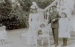 cinq personnes posent sur ce cliché, Geneviève, deux ans, debout et portant un petit chapeau, Henriette debout en tenue claire et coiffée d'un imposant chapeau à plumes, Emmanuel debout en tenue de ville, coiffé d'un képi, tenant un cigare de la main gauche, sa main droite étant posée sur le dossier d'un petit fauteuil sur lequel est assise Sophie coiffée d'une charlotte claire et tenant un petit chien au pelage sombre et debout à droite, Marie-Louise en tenue claire coiffée d'une large capeline