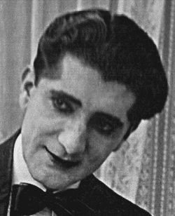 Photo en noir et blanc de la tête d'un homme aux traits maquillés et portant un nœud papillon