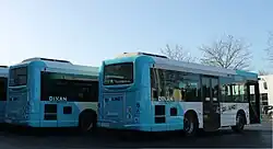Photo de l'arrière de deux bus de couleur blanc et turquoise.