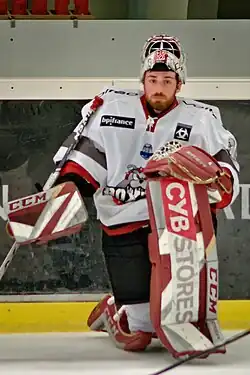 Gardien de but de hockey sur glace sur le bord de la patinoire, un genou posé au sol