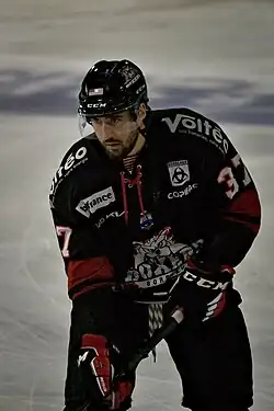 Joueur de hockey sur glace debout sur la glace, en équipement, regardant devant lui.