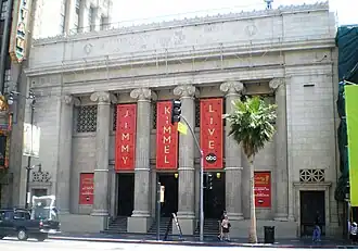 Façade à colonnades avec des 3 drapeaux rouges tendus entre les colonnes avec l'inscription Jimmy Kimmel Live en lettres dorées.