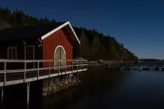 Lumière de lune sur un club de bateaux à Lysekil (commune), Suède. Dans le fond, les lumières de la route européenne 6. Novembre 2017.