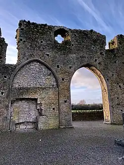 Photographie des arches gothiques d'une église en ruines, dont l'une a été murée.