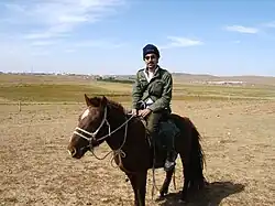 Un cheval roux foncé est monté par un touriste occidental.