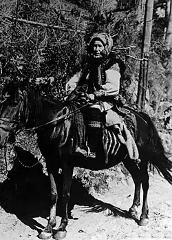 Photo en noir et blanc montrant une vieille femme sur un petit cheval.