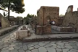 fontaine sur un angle de rues dallées brodées de trottoirs