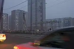 Photographie depuis le feneêtre d'une voiture de grands ensembles gris sur le côté de la rue.