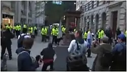 Plusieurs personnes sont debout parmi des bâtiments.