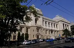façade néo-classique alternant symétriquement des arcades droites et des travées cintrées sur trois niveaux : les deux premiers présentent une maçonnerie à bossages gris pâle, le troisième une façade enduite de blanc