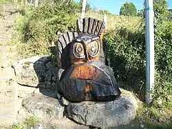 Un grand hibou sculpté en bois à l'entrée du village